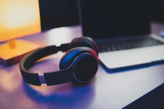 Headset preto sobre mesa com notebook ao fundo